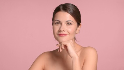 Brunette woman portrait watching to the camera. Pink background natural makeup