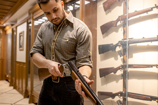 young man reload a rifle in guns store, man want to buy rifle for hunting. customer in weapons shop. firearm, hunter