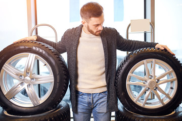 pleasant bearded man touching and choosing for buying a tire in a supermarket shop or DIY department store, close up photo.