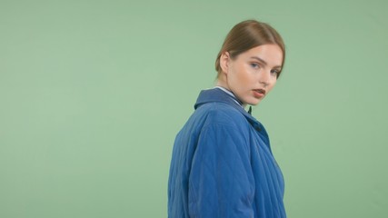 model in studio turning to the camera wears blue jacket