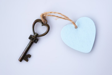 Heart shape antique key with pastel blue wooden heart keyring. Home sweet home concept.