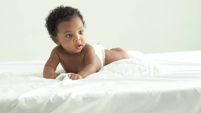 African baby boy is lying on the bed.he have beautiful eyes.