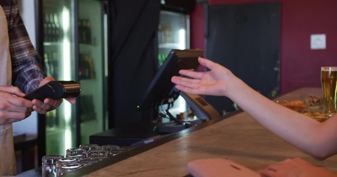 Woman giving her credit card to a bartender.