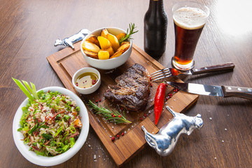 bifes de churrasco com acompanhamentos em tábua de madeira