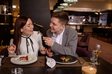 Try it! caucasian couple eat delicious food in luxury restaurant. young married couple treat each other with dessert. love, relationships, restaurant concept. indoors