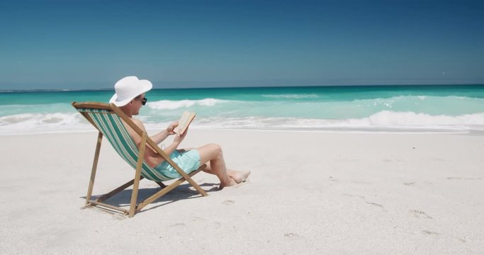 Man reading a book on the beach 