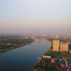 Obraz premium 07-01-2020 A bird's eye view of a building. The curved view of the Chao Phraya River, both sides of the house and hi rise of condominiums or residence. In Bangkok, Thailand. at sunset time