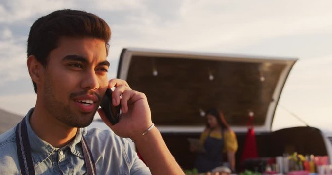 Young man talking on the phone by food truck