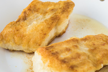 Fried light breaded cod fish.
