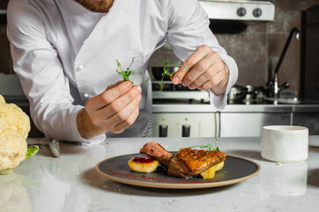 cropped caucasian chef-cook finishing delicious dish in the kitchen of restaurant. expert in culinary. food concept