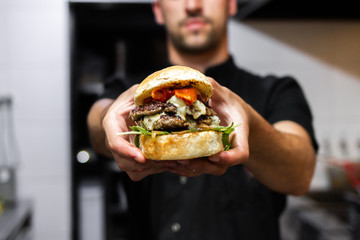 unrecognizable latin chef holding a prepared hamburger