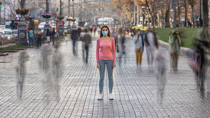 The woman with medical face mask stands on the crowded street