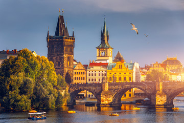 Naklejka premium Autumn view to Charles bridge on Vltava river in Prague, Czech Republic. Autumn view to Charles Bridge, Prague old town and Vltava river. Czechia. Scenic autumn view of the Old Town with red foliage.
