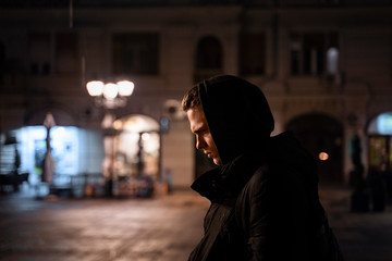 Depressed , lonely teenager walking the streets by night alone and thinking with head bowed 