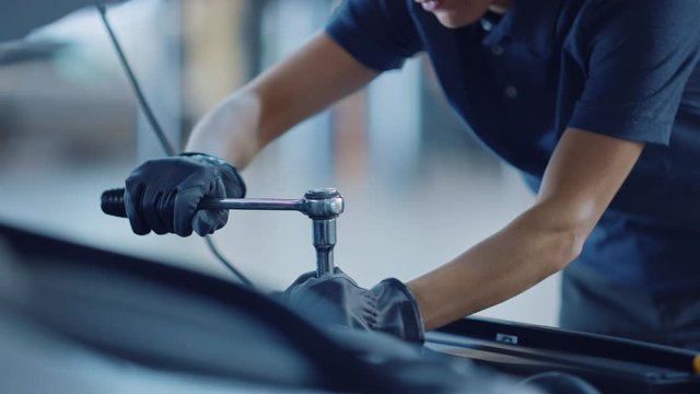 Slow Motion Close Up Footage of a Female Mechanic Working on a Car in a Car Service. Empowering Woman Makes an Usual Car Maintenance. She's Using a Ratchet. Modern Clean Workshop. 
