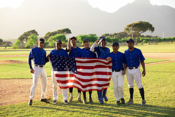 Portrait of baseball players standing with American flag in field