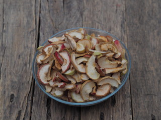 Background of dried homemade fruit Apple chips or slices in a glass plate on a wooden table. Health benefits of dried fruits, vegetarian food.
