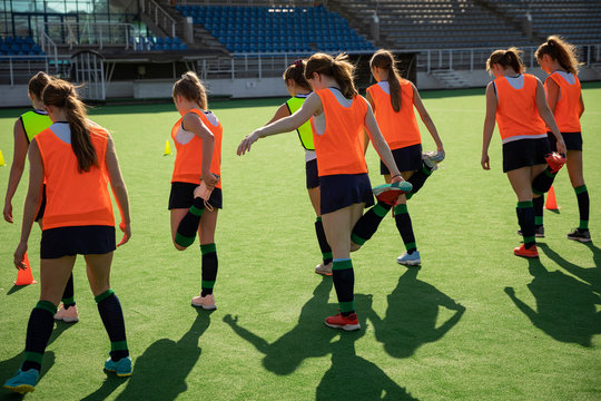 Female hockey players stretching on the field