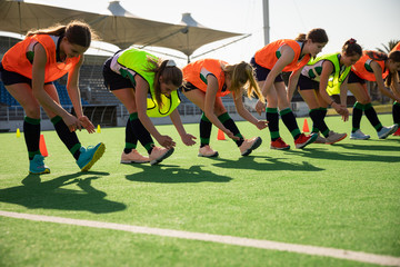 Female hockey players stretching on the field