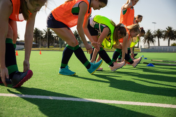 Female hockey players stretching on the field