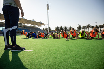 Female hockey players doing push-ups on the field