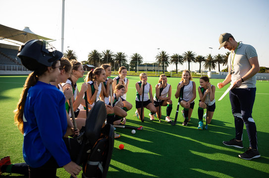 Female hockey players listening to the coach on the field