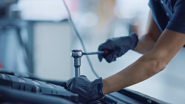 Slow Motion Close Up Footage of a Female Mechanic Working on a Vehicle in a Car Service. Empowering Woman Fixing the Engine. She's Using a Ratchet. Modern Clean Workshop. 
