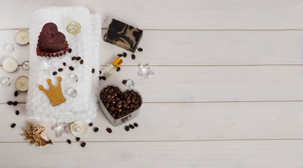 Royal chocolate and coffee spa treatment, massage as a gift. White towel, candle in the form of a heart, coffee beans, coffee soap, oil as a decor with copy space on a white background.