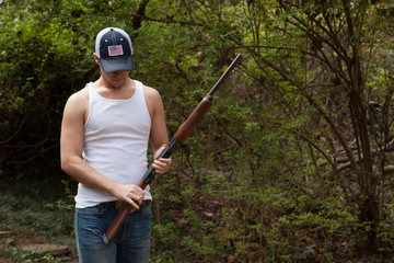 Fototapeta premium Thoughtful man with a shotgun in the woods