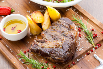 churrasco de bife de chorizo em tábua de madeira com batatas e alecrim