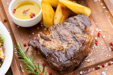 churrasco de bife de chorizo em tábua de madeira com batatas e alecrim