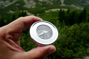 compass in the hands of a tourist, mountain landscape in the background, High Tatras mountain                  