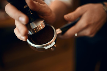professional talented barista prepares espresso in his coffee shop, blurred background.close up...