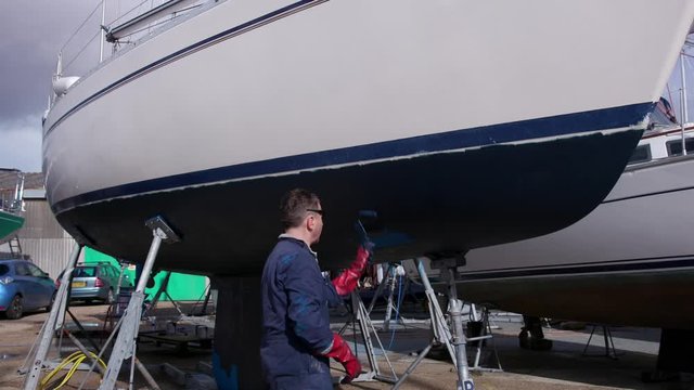 Sailing boat yacht being painted with antifoul paint in slow motion
