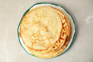 Stack of fresh thin pancakes on light grey marble table, top view