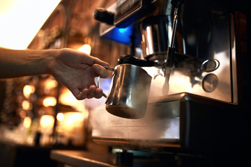 male bartender is in the workplace.man makes coffee using coffee machine. cappuccino, shop, the bartender