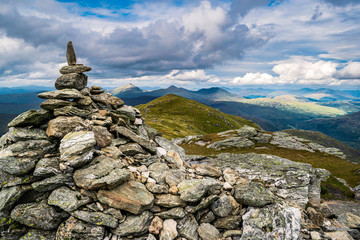 The cairn marking the peak of Ben Vorlich with the scenic Scottish Highlands landscape in the...