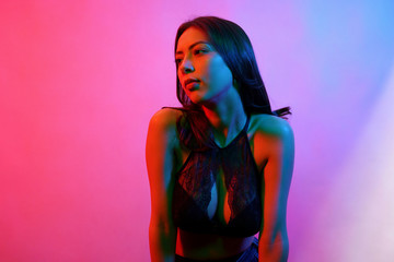 Beauty fashion portrait of female in black lingerie with colorful neon light