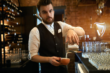 professional good loooking stylish barista pouring milk in a cup, looking at the camera, posing to...