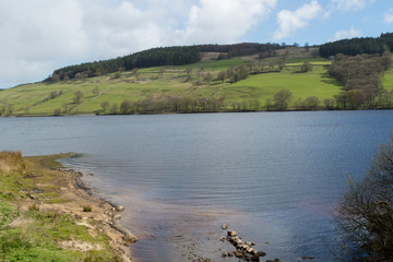 Tranquil water with hilly pastures and woodland in the background at Gouthwaite Reservoir,Nidderdale,which is situated between the small villages of Wath and Ramsgill,North Yorkshire.