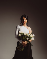 Portrays models in the studio on a dark background with white flowers.
