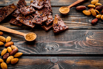 Homemade chocolate. Pieces, nuts on wooden table copy space