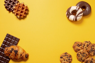 Sweet food frame on a yellow paper background. Top view