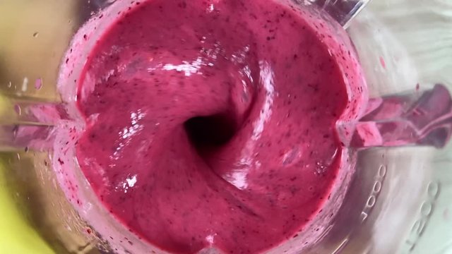 Mixing cranberry banana smoothie in a blender, close-up, super slow motion