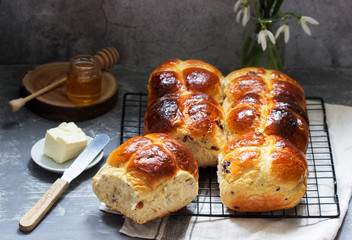 Traditional hot cross buns with honey and butter on a concrete background.