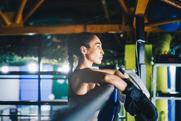 Fototapeta premium Female kickboxer resting on ring corner. 
