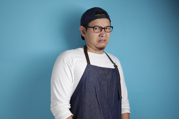 Portrait of young male Asian chef or waiter shows disgusted or displeased expression