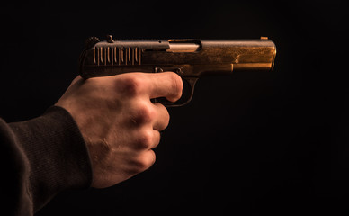 Naklejka premium The hand presses the trigger of the gun and the flame from the shot escapes from its muzzle