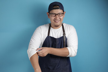 Portrait of happy proud Asian chef or waiter smiling at camera and rolling up his shirt sleeves, ready to work concept