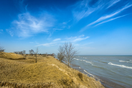 Lake Michigan waves crash against the dunes under a soaring blue sky at Kohler Andrae State Park, Wisconsin